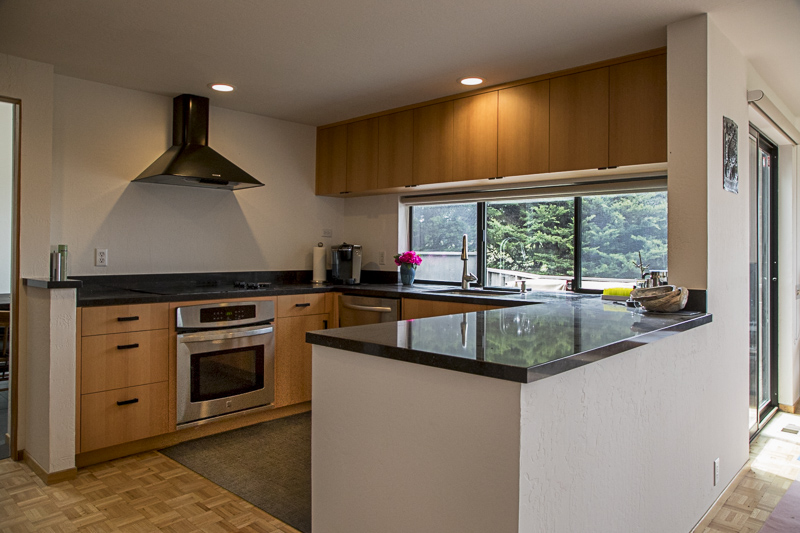 A view of the kitchen showing the stove and counter with a window looking out onto the garden.