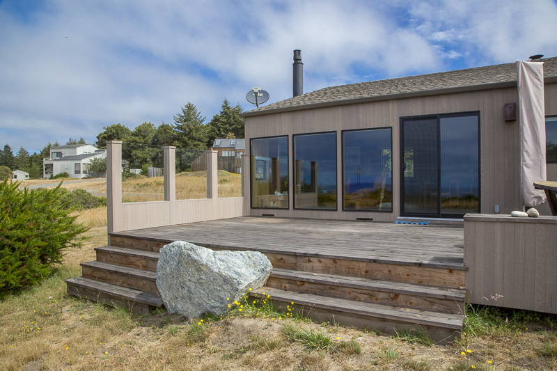 The back deck of a home with stairs down to the garden and a large rock embedded in the stairs.