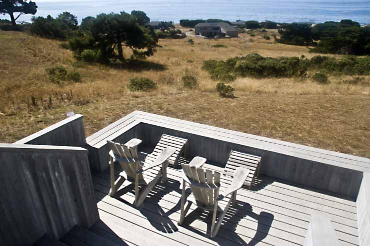 A deck with two chairs and a view of the ocean.